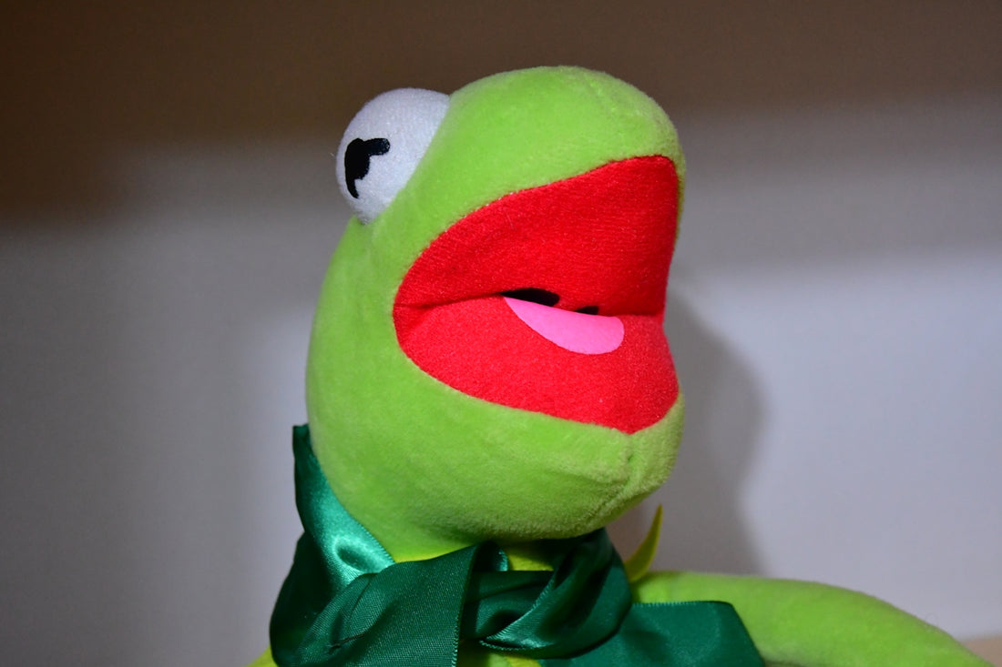 A kermit the frog plush toy with mouth open