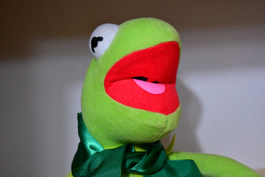 A kermit the frog plush toy with mouth open