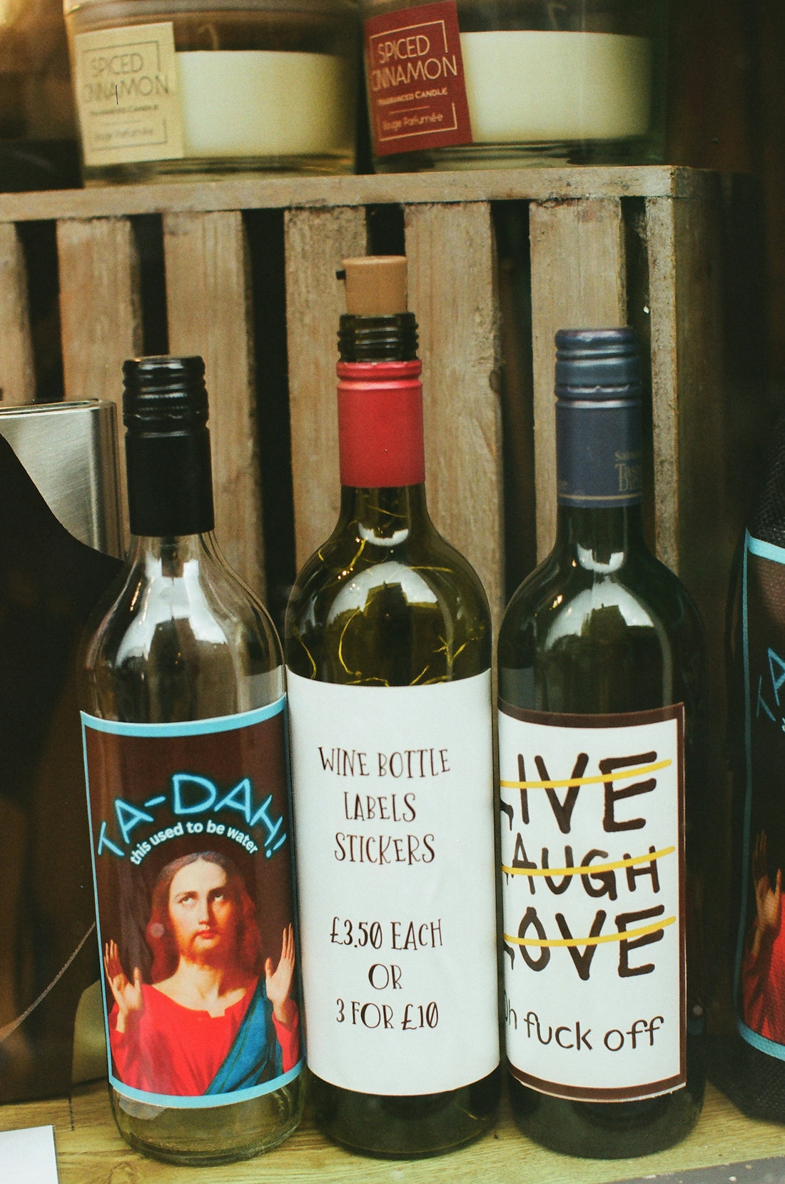 Three wine bottles with humorous labels displayed.